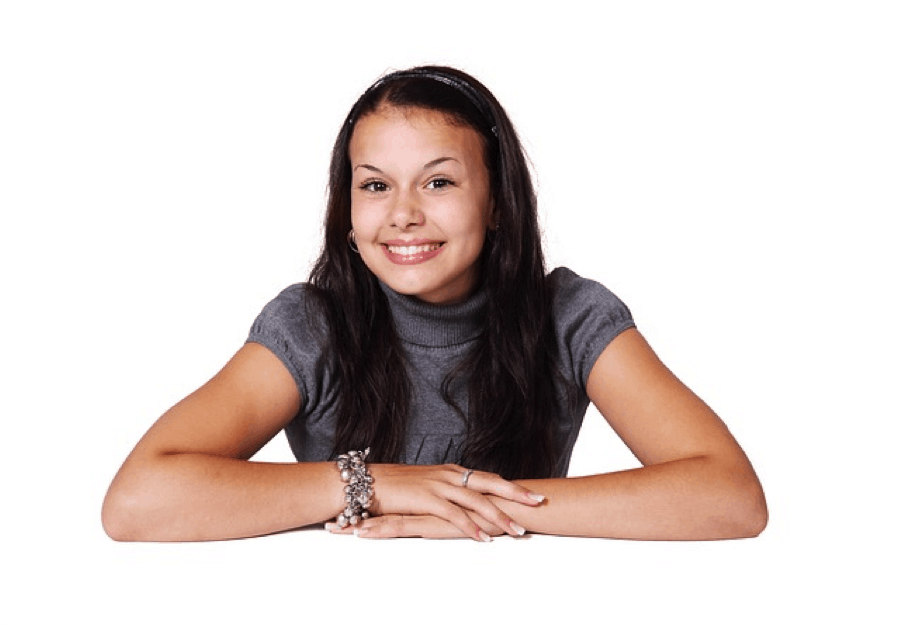 A young teenage girl smiling at the camera with her arms crossed as she promotes clean, healthy teeth.