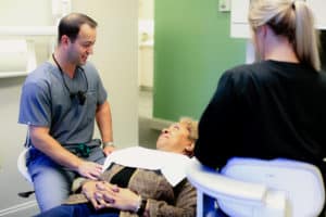 Older woman laying in dental chair talking to dentist