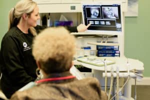 Dental assistant explaining x-ray to patient in dental chair